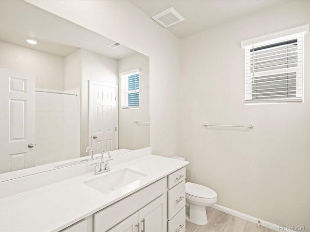 bathroom with toilet, visible vents, baseboards, a shower, and vanity
