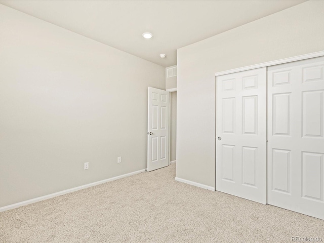 unfurnished bedroom featuring a closet, baseboards, and light carpet
