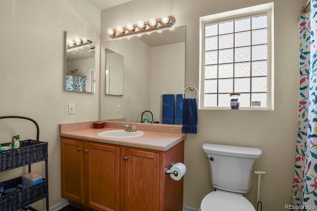 bathroom featuring a healthy amount of sunlight, vanity, and toilet