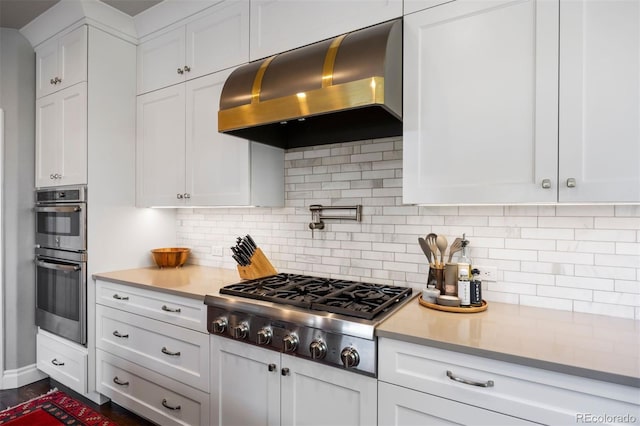 6175 Puma Sands, Lone Tree, CO 80124 - kitchen with ventilation hood, stainless steel appliances, light countertops, white cabinets, and tasteful backsplash