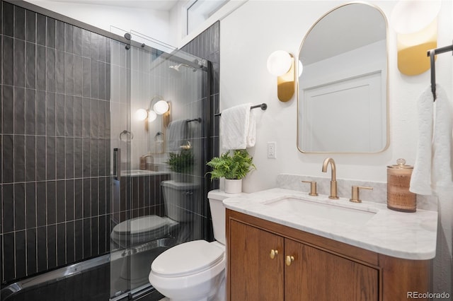 bathroom featuring toilet, a shower with shower door, and vanity