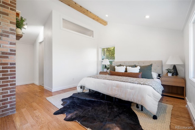 bedroom with lofted ceiling with beams and light wood-type flooring