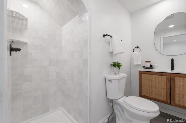 bathroom featuring toilet, vanity, and tiled shower