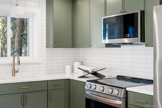 kitchen with appliances with stainless steel finishes, sink, decorative backsplash, and green cabinetry