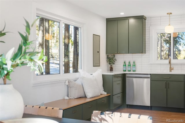 kitchen with decorative light fixtures, backsplash, stainless steel dishwasher, sink, and green cabinetry