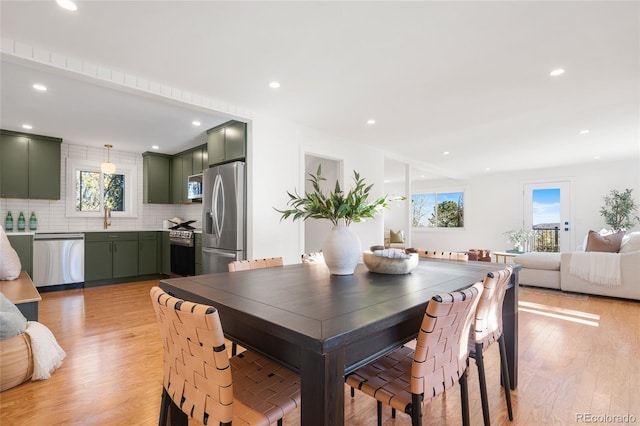 dining space featuring light wood-type flooring, a healthy amount of sunlight, and sink