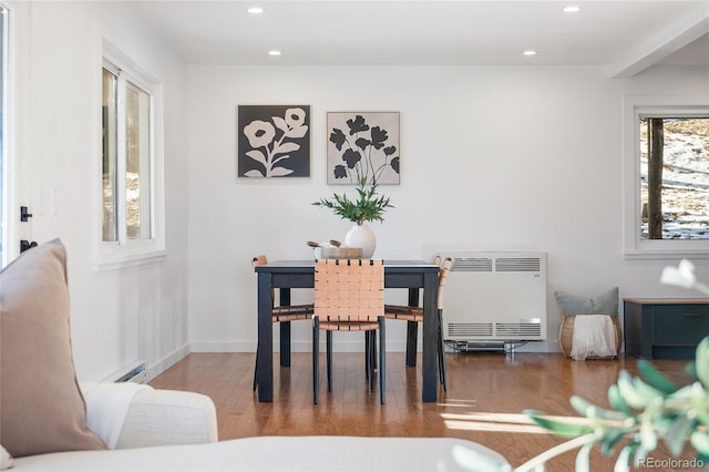 dining area with heating unit, wood-type flooring, and a baseboard radiator