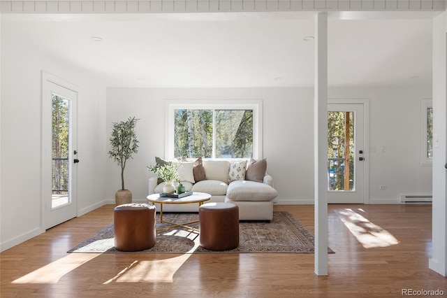 living room featuring a baseboard heating unit, hardwood / wood-style flooring, and plenty of natural light