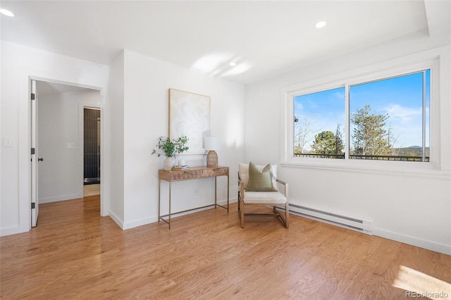 sitting room featuring baseboard heating and light hardwood / wood-style flooring