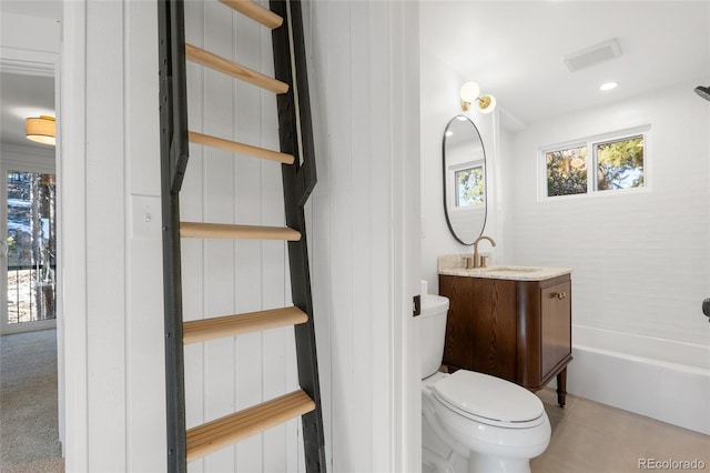 bathroom featuring toilet, vanity, and a tub to relax in