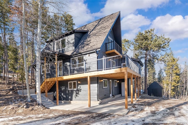 view of front of property featuring a patio area, a wooden deck, and a storage shed