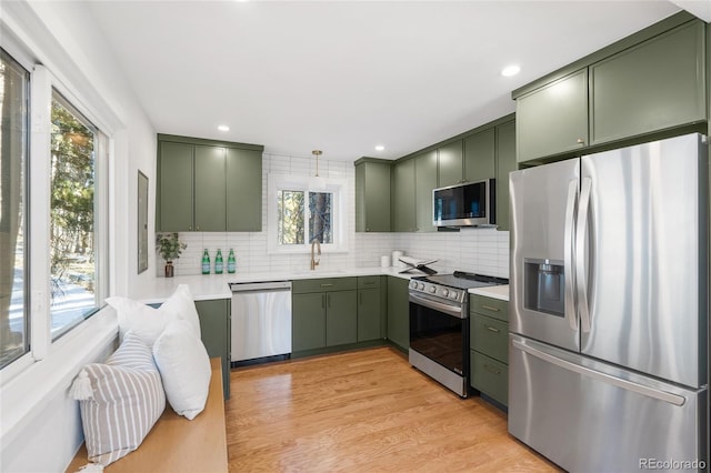 kitchen with tasteful backsplash, light hardwood / wood-style flooring, stainless steel appliances, and green cabinetry