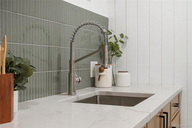 interior details with light stone counters, sink, and tasteful backsplash