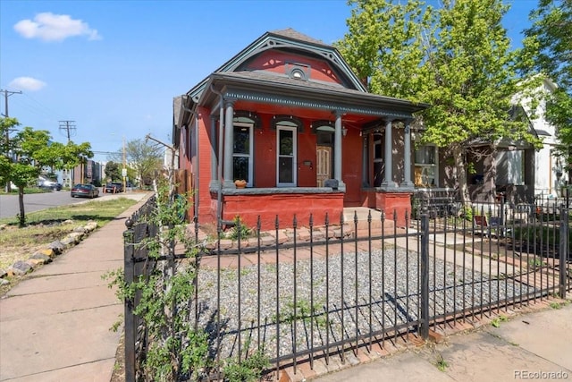 1103 Lipan St, Denver, CO 80204 - view of front of house featuring a porch, a fenced front yard, and brick siding