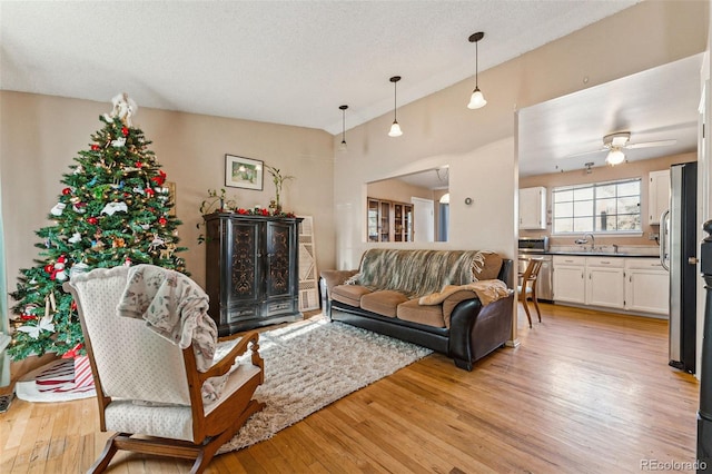 living room with lofted ceiling, sink, ceiling fan, a textured ceiling, and light hardwood / wood-style floors