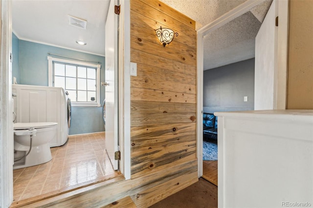 bathroom featuring washer / clothes dryer, a textured ceiling, and ornamental molding