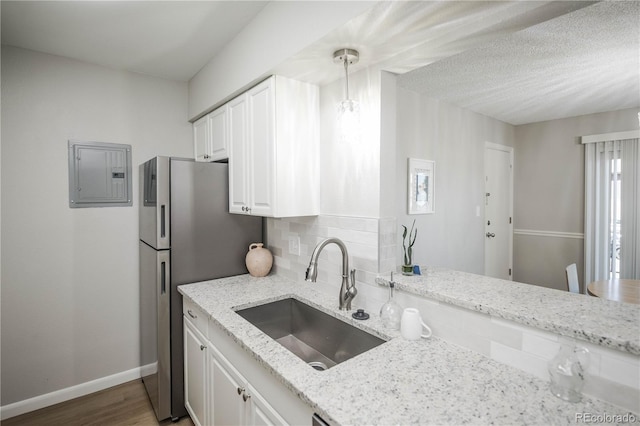 3855 S Monaco St Unit 208, Denver, CO 80237 - kitchen with electric panel, freestanding refrigerator, tasteful backsplash, light stone counters, and white cabinetry