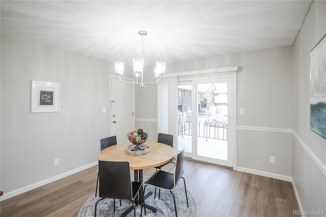 3855 S Monaco St Unit 208, Denver, CO 80237 - dining area featuring wood finished floors, a chandelier, and a textured ceiling