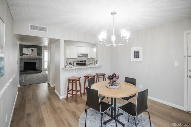 3855 S Monaco St Unit 208, Denver, CO 80237 - dining space featuring wood finished floors, a chandelier, a fireplace, and a textured ceiling