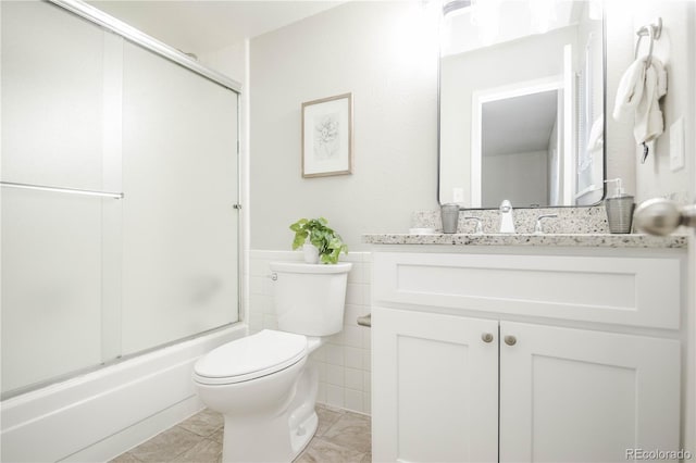 3855 S Monaco St Unit 208, Denver, CO 80237 - bathroom featuring vanity, combined bath / shower with glass door, tile walls, and wainscoting