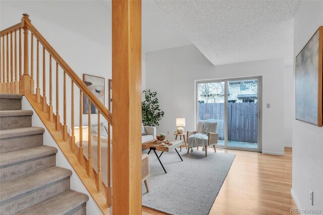 4248 Corriente Pl, Boulder, CO 80301 - stairs with wood finished floors, a textured ceiling, lofted ceiling, and baseboards