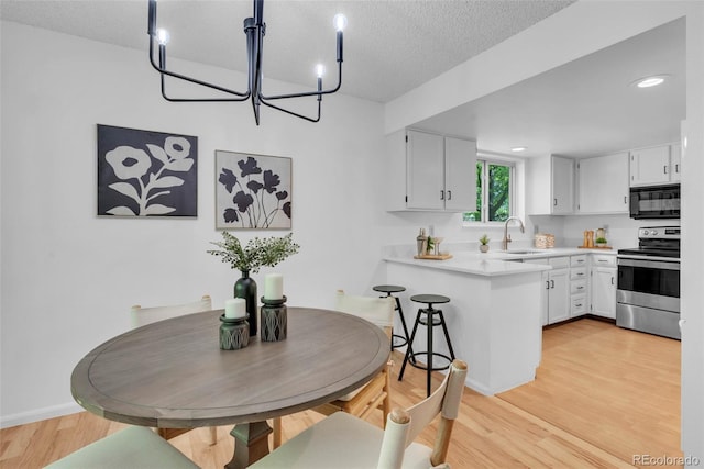 4248 Corriente Pl, Boulder, CO 80301 - kitchen featuring stainless steel range with electric cooktop, black microwave, a peninsula, light wood finished floors, and light countertops