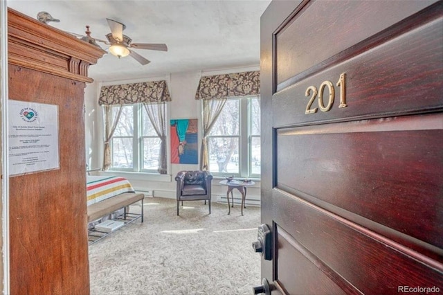 interior space with carpet floors, ceiling fan, and baseboard heating