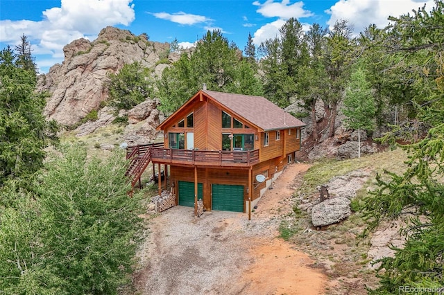 rear view of property with a wooden deck and a garage