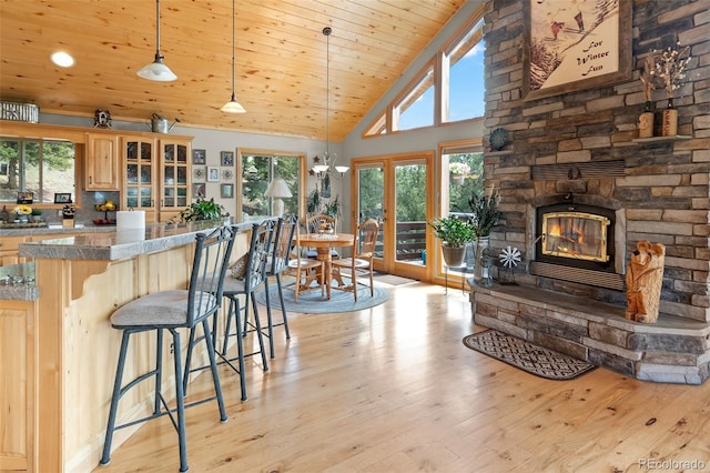 kitchen featuring light hardwood / wood-style flooring, a breakfast bar area, wooden ceiling, and decorative light fixtures