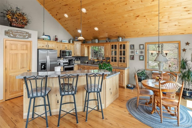 kitchen with light hardwood / wood-style floors, stainless steel appliances, a center island, and a kitchen bar