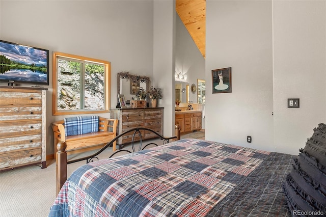 bedroom featuring ensuite bathroom, light carpet, and high vaulted ceiling