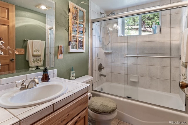 full bathroom featuring vanity, combined bath / shower with glass door, and toilet