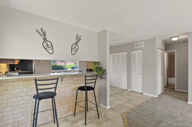 kitchen with a breakfast bar, visible vents, backsplash, and baseboards