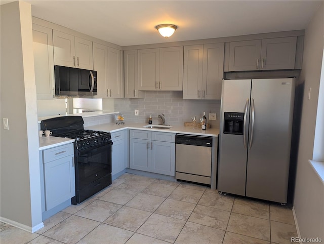 kitchen with baseboards, a sink, stainless steel appliances, light countertops, and backsplash