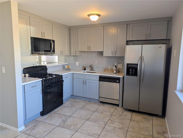 kitchen with stainless steel appliances, light countertops, backsplash, a sink, and baseboards