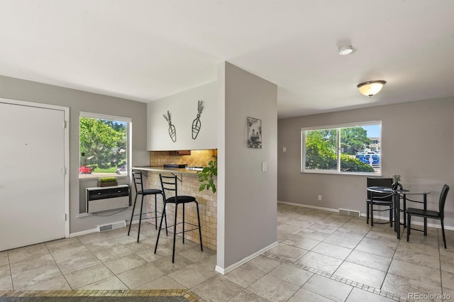 2246 N Coronado Pkwy Unit A, Denver, CO 80229 - kitchen featuring healthy amount of natural light, a breakfast bar area, light tile patterned floors, and baseboards