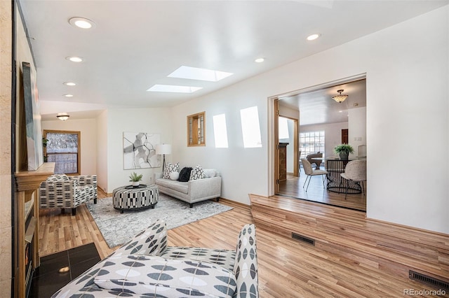 living room with a skylight, wood finished floors, visible vents, and recessed lighting