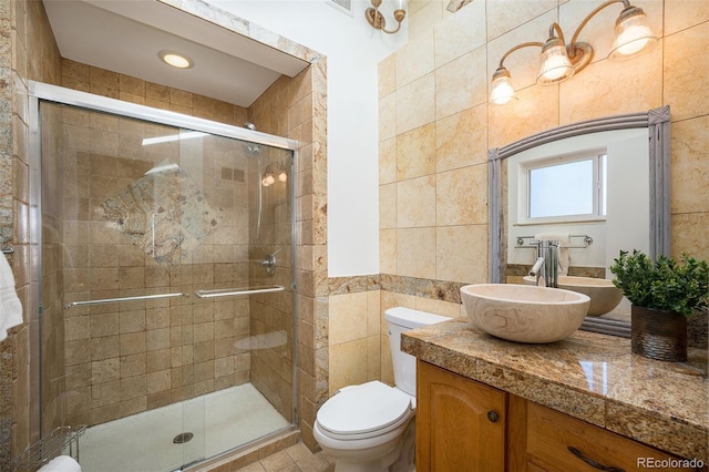 full bathroom with toilet, a stall shower, vanity, and tile walls