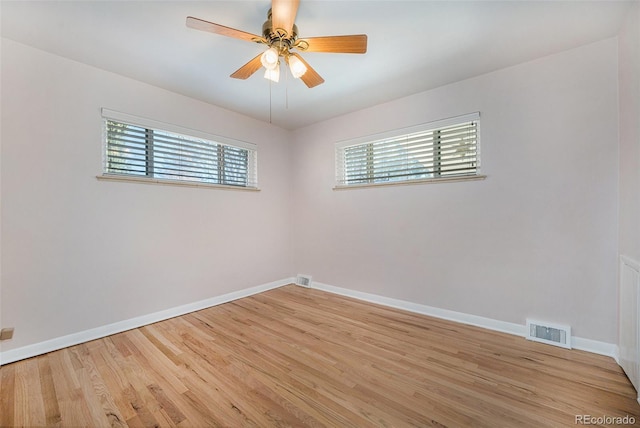 spare room featuring light wood finished floors, plenty of natural light, visible vents, and baseboards