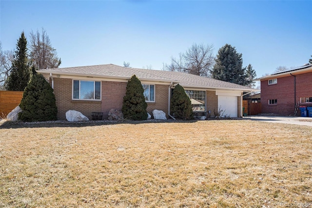 single story home featuring an attached garage, a front yard, and brick siding