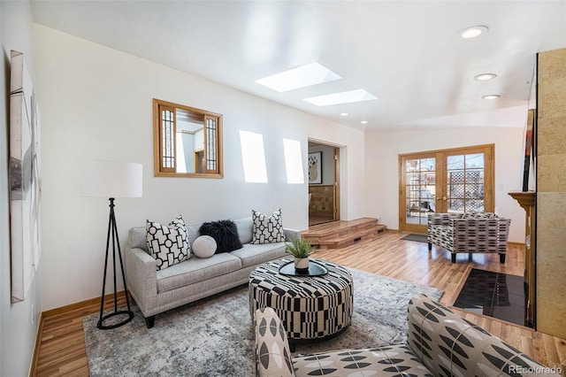 living room featuring a skylight, baseboards, wood finished floors, french doors, and recessed lighting