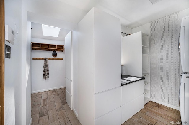 hallway with baseboards, a skylight, and wood tiled floor