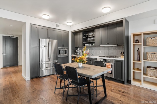 1750 Wewatta St Unit 525, Denver, CO 80202 - kitchen featuring appliances with stainless steel finishes, open shelves, decorative backsplash, and dark wood-style flooring