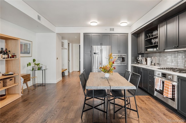 1750 Wewatta St Unit 525, Denver, CO 80202 - kitchen featuring stainless steel appliances, open shelves, light countertops, backsplash, and wood finished floors