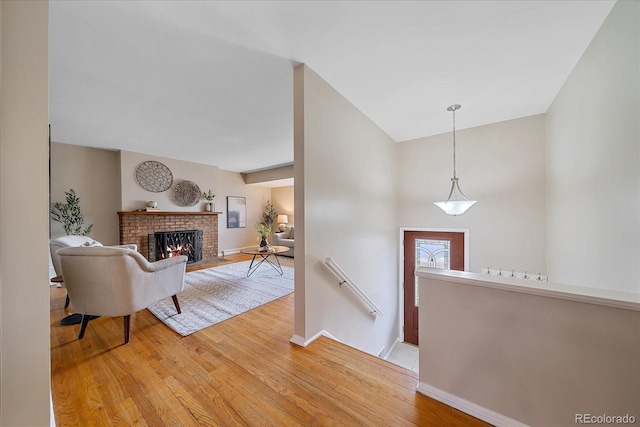 foyer entrance featuring baseboards, light wood-style floors, and a brick fireplace