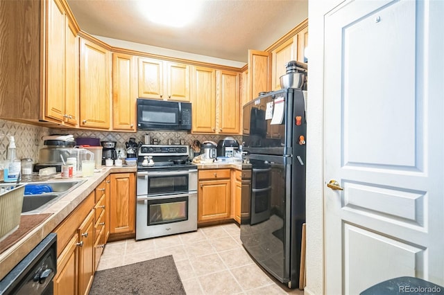 kitchen featuring tasteful backsplash, light countertops, black appliances, and light tile patterned floors