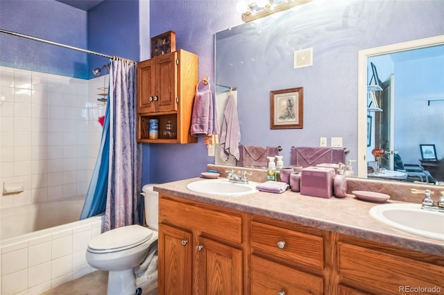 bathroom featuring double vanity, tiled shower / bath combo, a sink, and toilet