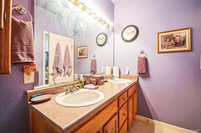 full bath featuring double vanity, tile patterned flooring, a sink, and baseboards