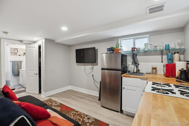 190 W Archer Pl, Denver, CO 80223 - kitchen with visible vents, freestanding refrigerator, butcher block counters, light wood-style floors, and white cabinetry