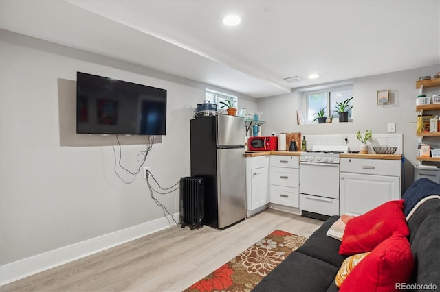190 W Archer Pl, Denver, CO 80223 - kitchen with light wood-style floors, radiator heating unit, white gas range, freestanding refrigerator, and white cabinetry